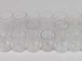 twelve clear glasses lined up in a row on a white surface
