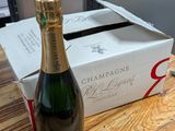 une bouteille de champagne posée sur une table à côté d'un carton de vin