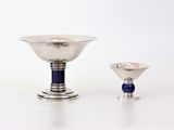 un bol en argent et un verre bleu posés sur une table