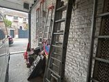 plusieurs échelles appuyées contre un mur de briques, à côté d'une camionnette