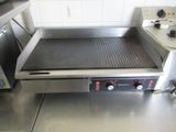 stainless steel counter top with an electric griddle on it in a commercial kitchen
