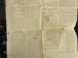 quelqu'un tient un journal sur lequel est posé une très grande feuille de papier