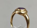 a close up of a gold ring with a purple stone on it