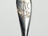 a spoon with a monogram on it sitting on a table