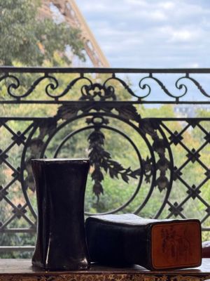 a vase and a book on a table in front of the eiffel tower