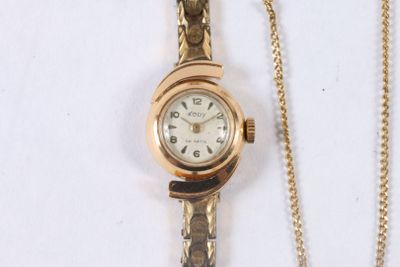 a gold wrist watch with a chain on a white surface