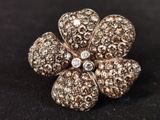 a close up of a diamond flower ring on a black surface