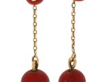 une paire de boucles d'oreilles avec des perles rouges et des chaînes dorées