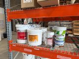 plusieurs seaux de peinture posés sur une étagère dans un entrepôt