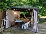 a gazebo on a wooden deck with a table and chairs
