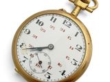 gros plan d'une montre de poche en or sur une surface blanche