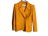 une veste orange suspendue à un cintre sur un mur blanc