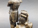 a bronze figurine of a man standing on a rock with a dog