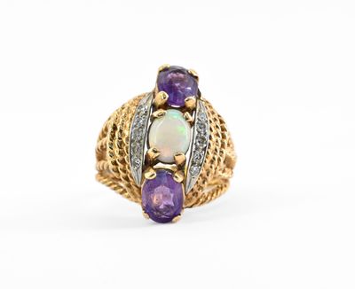 un gros plan d'une bague en or sertie d'une pierre violette et blanche