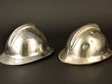 two silver hard hats sitting on a black surface