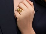 the woman is wearing a gold ring and a black blazer