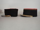 pair of black and red hats with gold trims on a white surface