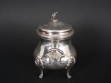 an antique silver teapot with a lid on a black background