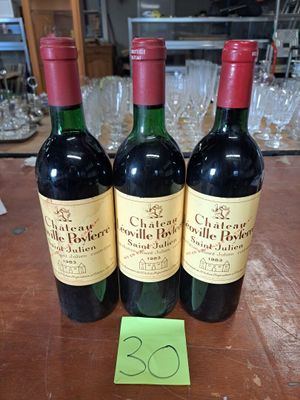 trois bouteilles de vin posées sur une table, à côté d'une étiquette de prix