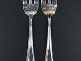 two forks and a spoon on a black background