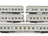 four silver train cars sitting on top of each other on a white surface