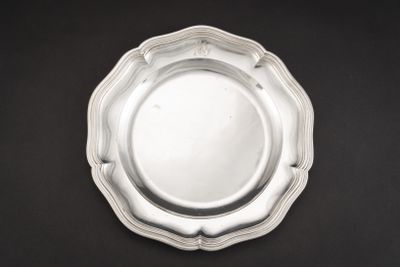 une assiette en argent posée sur une table noire, sur fond noir