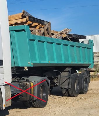 un camion-benne vert garé à côté d'un immeuble