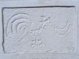 a stone block with a rooster and a bird carved into it