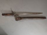 pair of old swords on a white surface with a wooden handle