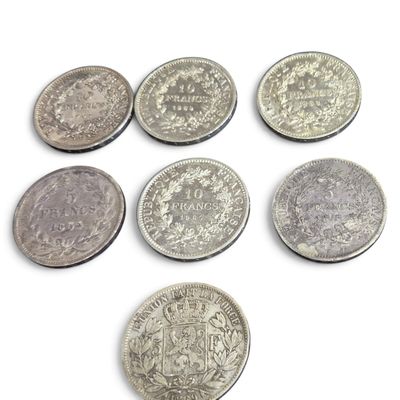 six types différents de pièces d'argent sur une surface blanche