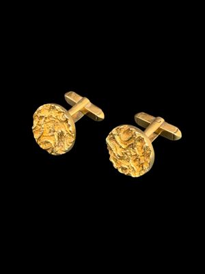 a pair of gold cufflinks on a black background