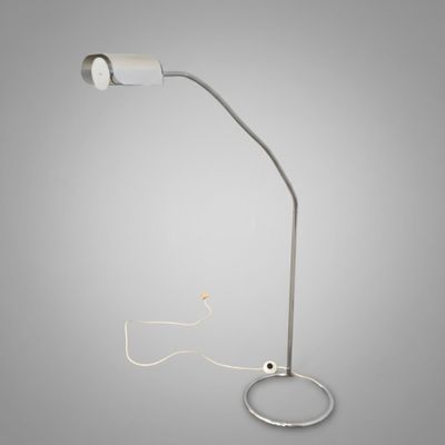 une lampe blanche reliée à un cordon, sur fond gris