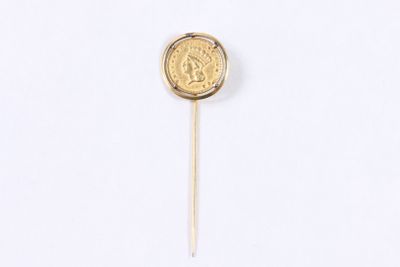a close up of a gold coin on a stick on a white surface