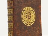 an old book with a gold medallion on it sitting on a white surface