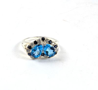 une image représentant une bague ornée de pierres bleues et noires sur un fond blanc