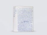 un livre ouvert, sur lequel figurent des inscriptions en bleu, posé sur une surface blanche