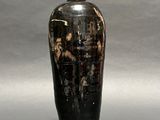 a black and gold vase sitting on a gray surface