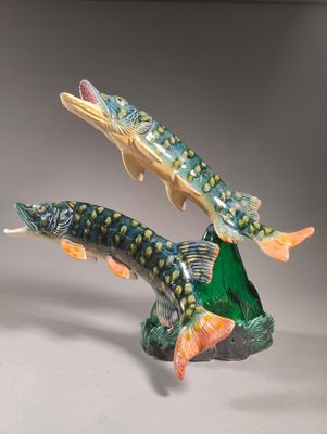 two figurines of two fish on top of a rock on a table
