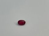 a single red stone sitting on top of a white surface