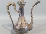 une théière en argent avec une anse sur une table
