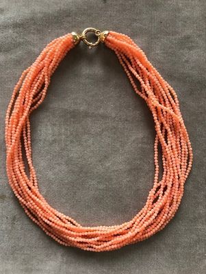 un gros plan d'un collier orange posé sur une surface grise