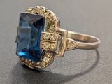 an image of a ring with a blue stone surrounded by diamonds