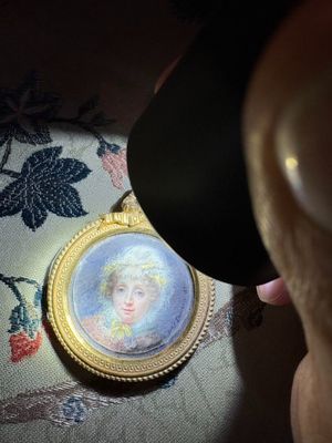 a person looking at a picture of a woman in a gold frame