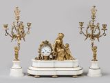 une horloge posée sur une table, à côté de trois chandeliers