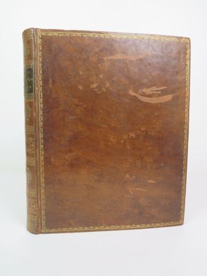 an old book with a brown cover sitting on top of a white surface