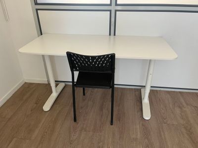 a white desk with a black chair in front of a window