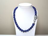collier de perles bleues orné d'un pendentif en forme de crâne argenté, porté par un mannequin blanc