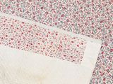 a white blanket with red and blue flowers on it