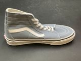 grey and white high top sneakers with white laces on a black surface