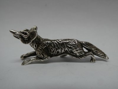une figurine représentant un renard argenté sur fond blanc